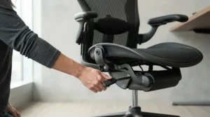 Hand operating the gas lift lever on a modern task chair with adjustable arms